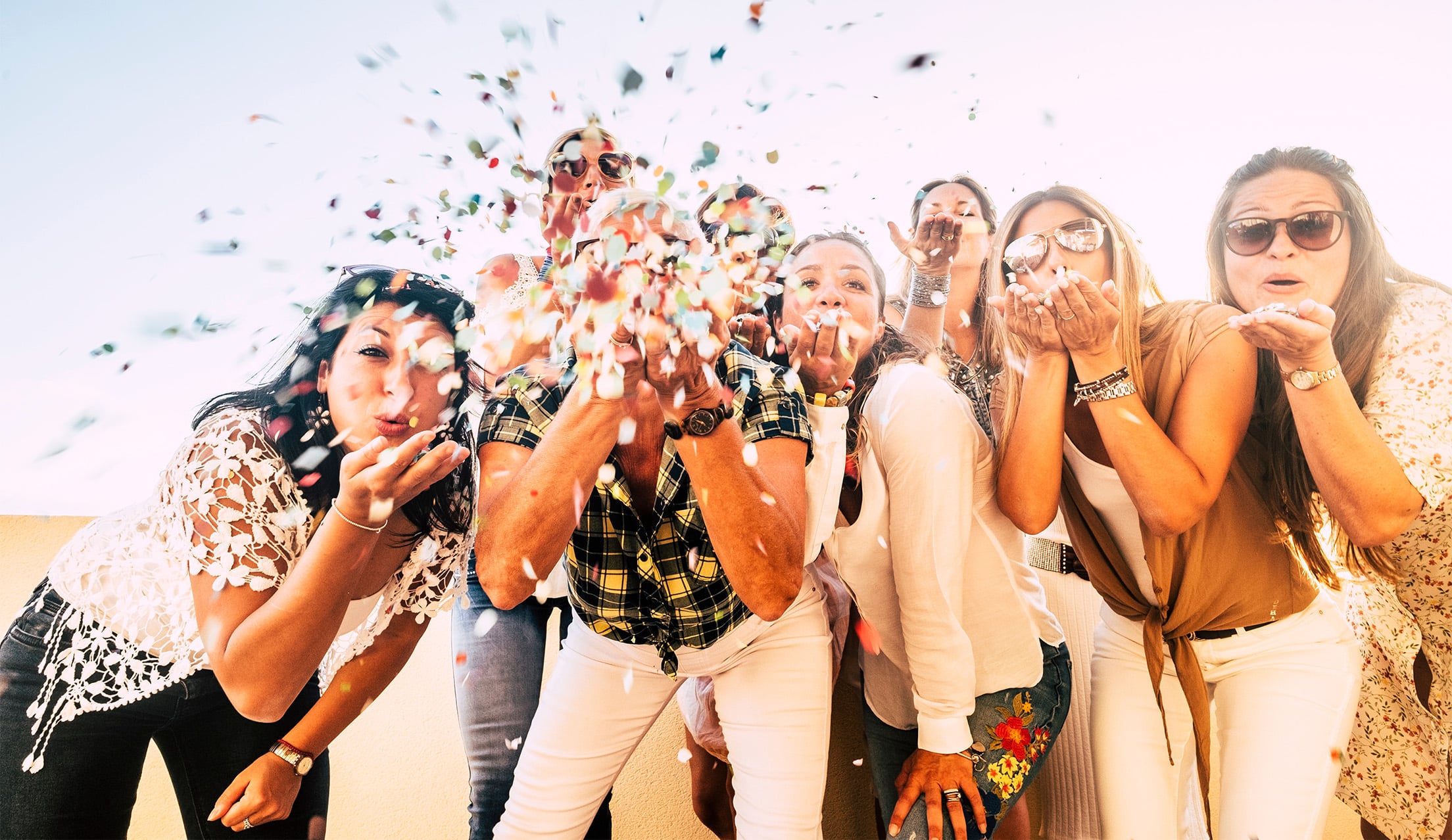 Group of bridesmaids blowing confetti